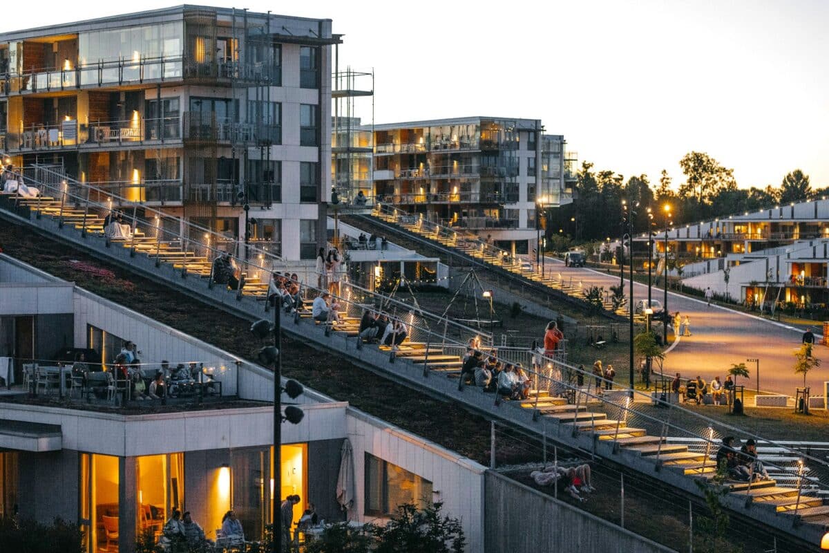 Folk på takene på hotellbyggene på Oslofjord Convention Center. Sommer, skumring.